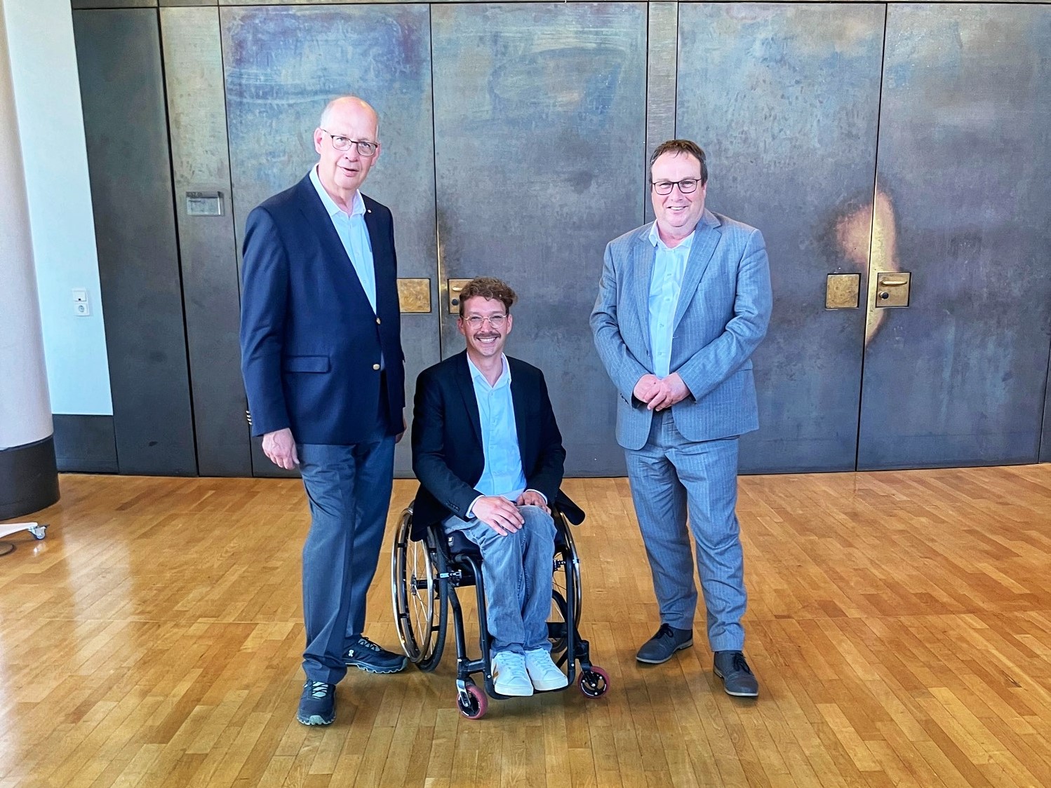 Auf dem Bild sieht man NRW-Bahnchef Werner Lübberink, Dennis Sonne und den NRW-Verkehrsminister Oliver Krischer im Foyer vor dem Plenarsaal des Landtags.